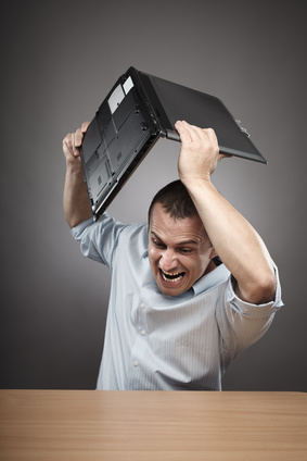 Extremely angry businessman smashing his laptop on the desk
